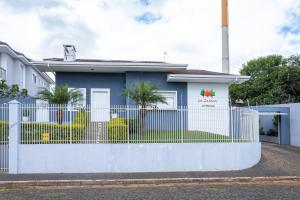 a blue house with a white fence at Pousada La Casona in Tibagi