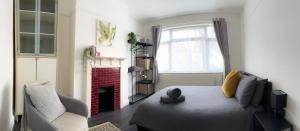 a bedroom with a bed and a chair and a fireplace at Modern four bedroom semi-detached house with off street parking 8 min drive to Wembley stadium, 5 miles to Central London in London
