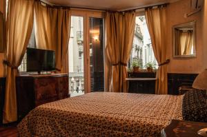 Schlafzimmer mit einem Bett, einem TV und einem Fenster in der Unterkunft DEL900 Hotel Boutique in Buenos Aires