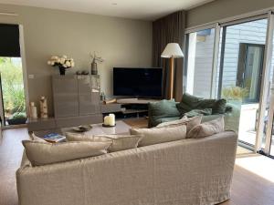 ein Wohnzimmer mit einem Sofa und einem Flachbild-TV in der Unterkunft Embruns et Sarrasin in Combrit