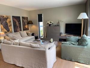 ein Wohnzimmer mit 2 Sofas und einem Flachbild-TV in der Unterkunft Embruns et Sarrasin in Combrit