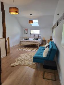 ein Wohnzimmer mit einem blauen Sofa und einem Bett in der Unterkunft Le Hangar in Coutures