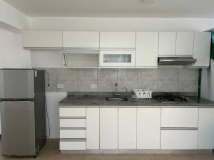 cocina con armarios blancos, fregadero y nevera en Apartamento familiar de lujo (402), en San Bartolo