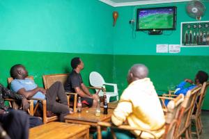 un groupe de personnes assises dans une pièce jouant à un jeu vidéo dans l'établissement Moments Lodge, à Lilongwe