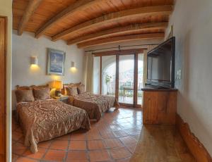 a bedroom with two beds and a flat screen tv at Casona Colonial de la Misión in Taxco de Alarcón