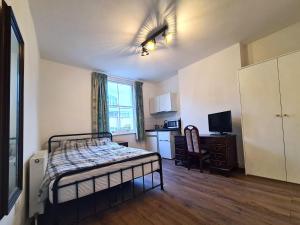 a small bedroom with a bed and a kitchen at The Greenwich Pensioner Guesthouse in London