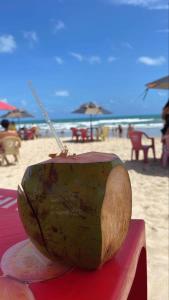 - une noix de coco assise sur une table à la plage dans l'établissement Pousada Caraguatatuba Praia Indaia Quarto 02, à Caraguatatuba