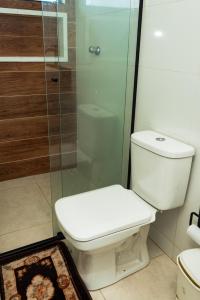 La salle de bains est pourvue de toilettes et d'une douche en verre. dans l'établissement Pousada Caraguatatuba Praia Indaia Quarto 02, à Caraguatatuba