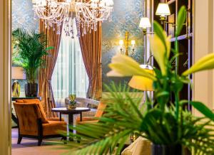 a living room with a chandelier and plants at Grand Hotel Casselbergh in Bruges
