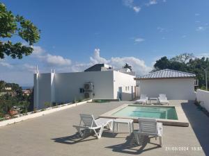 una casa dotata di patio con sedie e piscina. di Samaná Suites Hotel a Santa Bárbara de Samaná