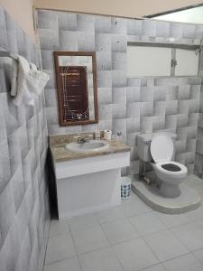 a bathroom with a toilet and a sink and a mirror at Arnold's Guest House in San Ignacio