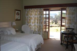 a bedroom with two beds and a sliding glass door at Olive Hill Country Lodge in Bloemfontein