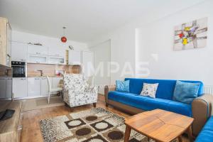 a living room with a blue couch and a kitchen at Simple Apartment in Prishtinë