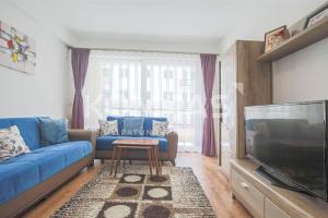 a living room with a blue couch and a tv at Simple Apartment in Prishtinë