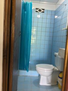 a bathroom with a toilet and a blue shower curtain at rooms megi terminal in Cahuita