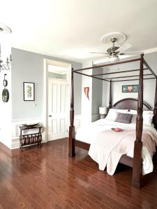 sypialnia z łóżkiem z baldachimem i drewnianą podłogą w obiekcie La Demeure du Capitaine w mieście Neuville