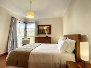 a bedroom with a large bed and a window at Charming Garajau by AH in Caniço