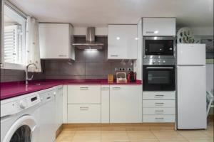 a kitchen with white cabinets and a washer and dryer at Villa del Mar in Puebla de Farnals