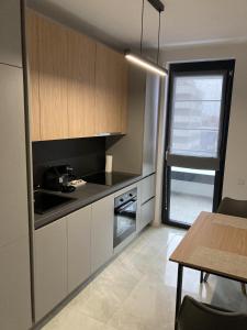 a kitchen with white cabinets and a table and a window at MEB Apartments - Park Lake in Cluj-Napoca