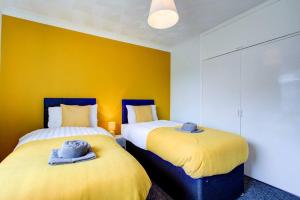 two beds in a room with yellow walls at Lovely 2 Bed Apartment near the Sea in Lancing