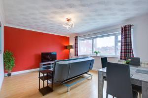 a living room with a red wall and a dining room at Lovely 2 Bed Apartment near the Sea in Lancing