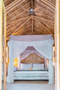 ein Schlafzimmer mit einem Himmelbett in einer Holzdecke in der Unterkunft Rose luxury 2 BR tropical eden forest view in Sukawati