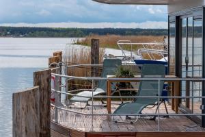 a dock with chairs and a table and a boat at Hausboot LP7 in Peenemünde