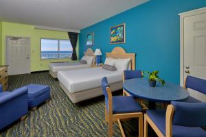 een hotelkamer met 2 bedden en 2 tafels en stoelen bij Palmetto Beachfront Hotel, a By The Sea Resort in Panama City Beach