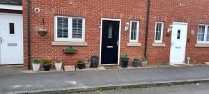 a brick house with potted plants in front of a door at Aylesbury Lovely Double and Single Bedroom with Guest only Bathroom in Buckinghamshire