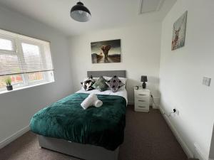a bedroom with a bed with a green blanket at Spacious 5 Bed House in Exhall