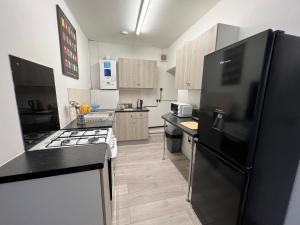 uma cozinha com um frigorífico preto e um fogão em Spacious 5-bed house in Coventry by Seeka Stay, Ideal for business, Sleeps 7! em Exhall