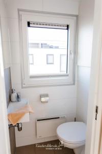 a bathroom with a white toilet and a window at Hausboot KranichNest in Ribnitz-Damgarten