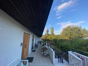 a porch of a white house with a wooden door at Stockholm stort Rum - Dator Arbetsplats Gratis Wifi 1Gb Fiber Parkering Garderober Room2 in Täby
