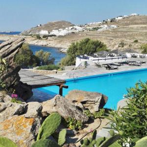 a large blue swimming pool next to a body of water at PARIS HOUSE in Mikonos