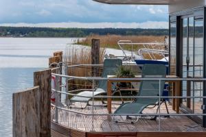 a dock with chairs and a table and a boat at Hausboot LP1 in Peenemünde