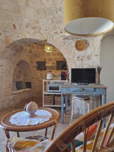 ein Wohnzimmer mit einem Tisch und einer Steinmauer in der Unterkunft Residenza Anima Mediterranea in Francavilla Fontana