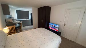 Schlafzimmer mit einem Bett und einem Flachbild-TV in der Unterkunft Apartment suites in Broughton, Milton keynes in Broughton