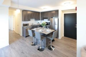 a kitchen with a table with chairs and a refrigerator at Luxurious Condo Apartment 2BRs-1BAs-1Office with free parking in Brampton