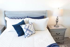 a bed with blue and white pillows and a lamp at Luxurious Condo Apartment 2BRs-1BAs-1Office with free parking in Brampton