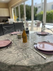 a table with pink plates and a yellow bottle on it at Maison de famille avec clim, piscine et parking in Nîmes