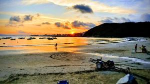 uma moto deitada na praia ao pôr do sol em Cabanas São Miguel em Penha
