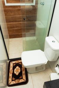 a bathroom with a toilet and a glass shower at Pousada Caraguatatuba Praia Indaia Quarto 04 in Caraguatatuba