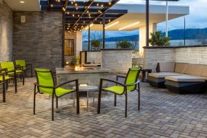 patio z zielonymi krzesłami i kanapą w obiekcie SpringHill Suites by Marriott Pleasanton w mieście Pleasanton