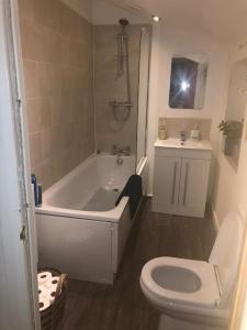 a bathroom with a white tub and a toilet at Just the Splott! Sleeps 6, 8 mins to Stadium. in Cardiff