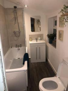 a bathroom with a toilet and a tub and a sink at Just the Splott! Sleeps 6, 8 mins to Stadium. in Cardiff