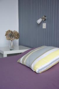 a bed with a purple and yellow pillow and a lamp at Hôtel Des Deux Mers in Saint-Pierre-Quiberon
