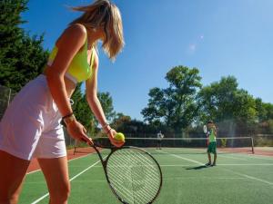 a woman holding a tennis ball and racket on a tennis court at Vacances en Provence en mobil home in La Roque-dʼAnthéron