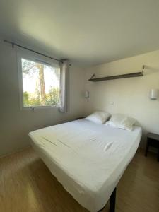 a white bed in a room with a window at Vacances en Provence en mobil home in La Roque-dʼAnthéron