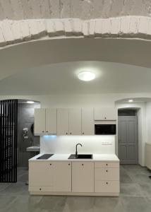 una cocina con armarios blancos y fregadero en Pension Phoenix en Znojmo