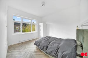 um quarto branco com uma cama e uma janela em Entire 2 bed flat London Zone 1-4 with private garden em Londres